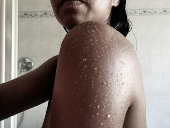 Rear view of shirtless woman in bathroom