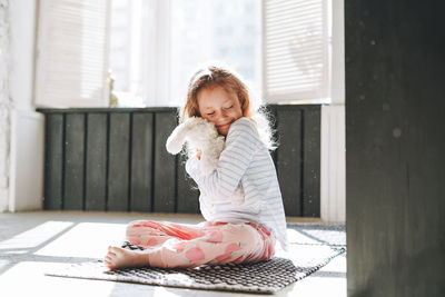 Cute little girl having fun with toy at bright bath room at home