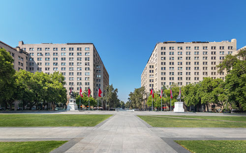 Road amidst buildings against clear sky