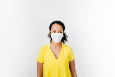 Portrait of mid adult woman wearing mask standing against white background