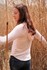 Young woman looking away while standing on field