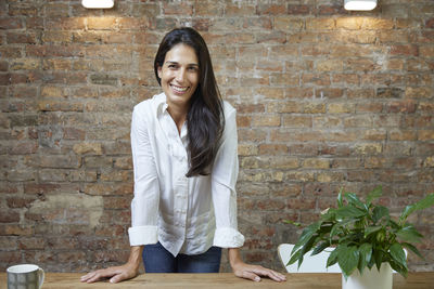 Young woman standing against brick wall