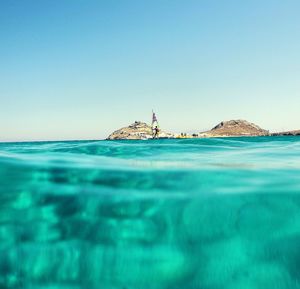 Swimming pool by sea against clear blue sky