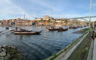 Sailboats in river by buildings in city against sky