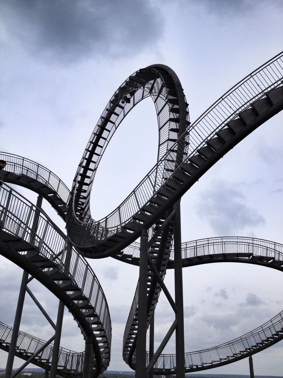 low angle view, sky, built structure, architecture, engineering, metal, bridge - man made structure, connection, metallic, cloud - sky, amusement park, arts culture and entertainment, amusement park ride, ferris wheel, cloud, famous place, international landmark, travel destinations, no people, bridge