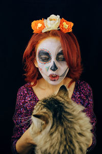 Portrait of a young woman wearing mask against black background