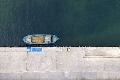 Aerial top view by drone of the moored small fishing boat at the quay.