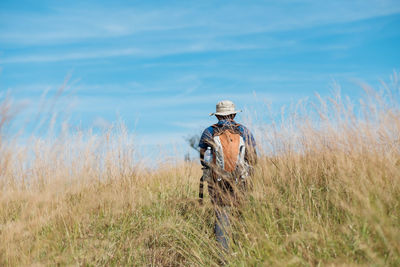 Rear view of man standing on field against sky