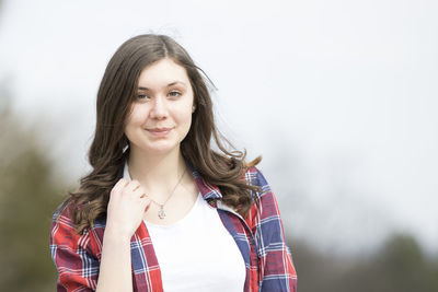 Portrait of smiling young woman standing against sky