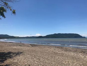 Scenic view of beach against clear blue sky