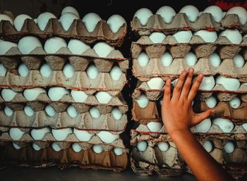 Cropped hand touching stack of egg cartons