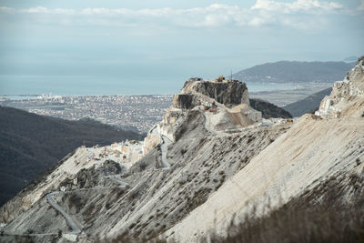 Scenic view of rocky mountains by sea against sky