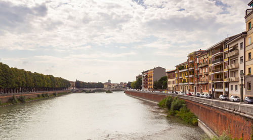 Canal amidst buildings in city against sky