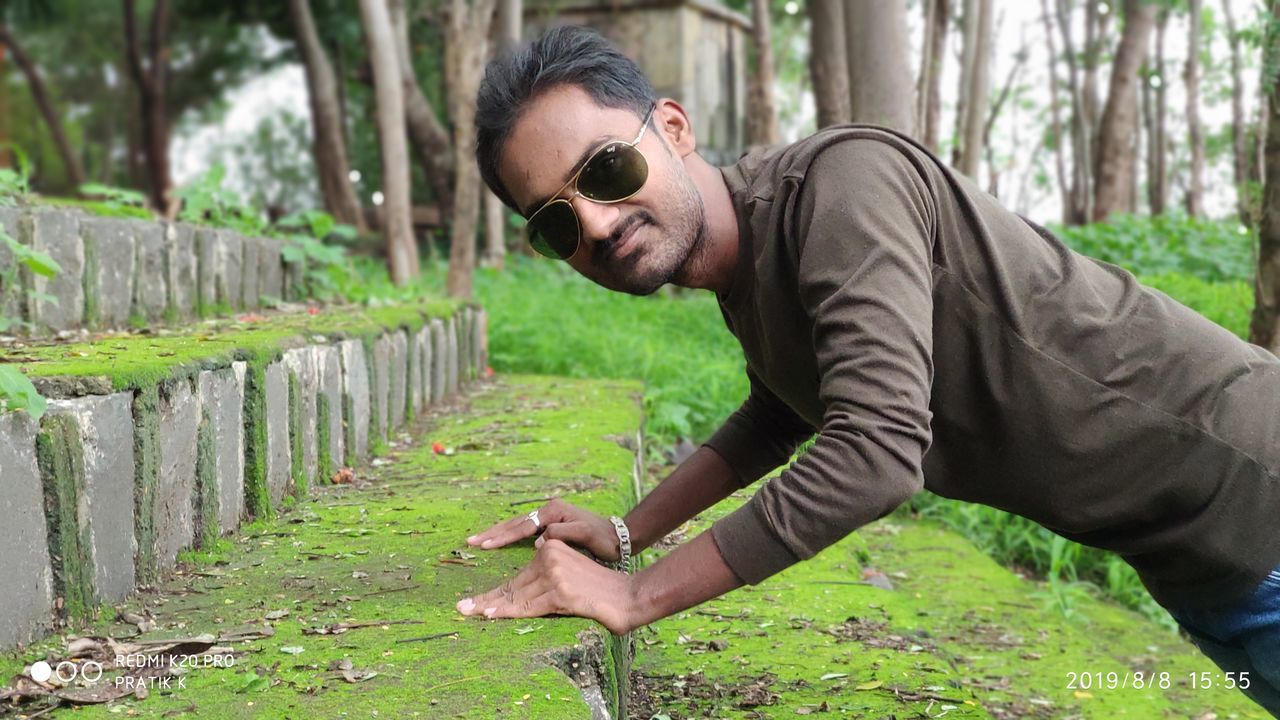 SIDE VIEW OF A MAN WEARING SUNGLASSES ON LAND