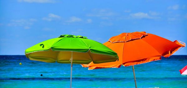 Close-up of yellow umbrella on beach against sky