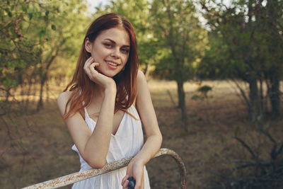 Portrait of smiling young woman against trees