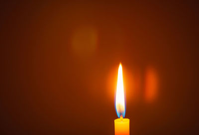 Close-up of lit candle against dark background