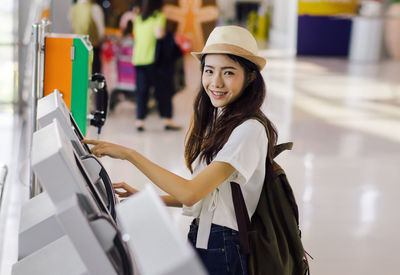 Portrait of smiling young woman making a reservation at airport