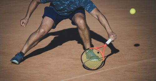 Low section of man playing tennis on court