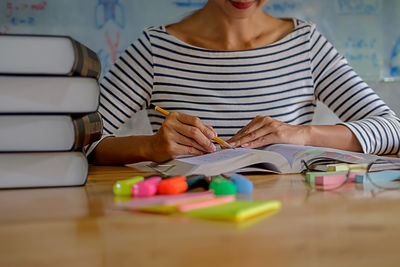 Woman studying with school supplies on table at home