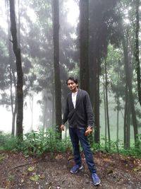 Full length portrait of young man standing in forest