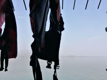 Low section of man standing by sea against sky