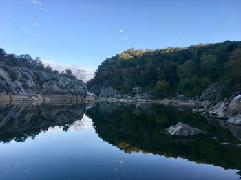 Scenic view of lake by trees against sky