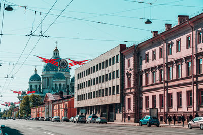 Cars on city street by buildings against sky