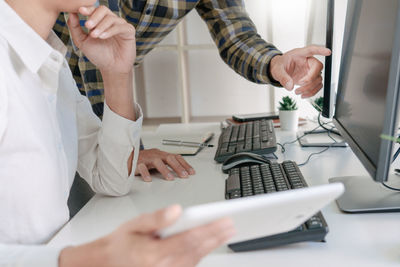 Midsection of programmers working on table