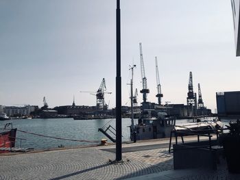 Cranes at harbor against sky