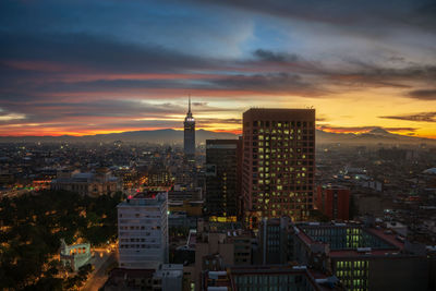 Aerial view of illuminated buildings against sky during sunset