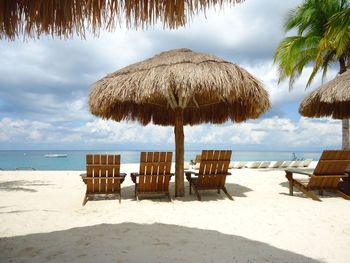 Deck chairs on beach against sky