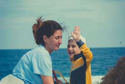 Mother and son standing on beach against clear sky