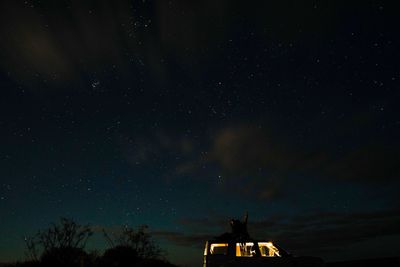 People sitting on car against star field at night