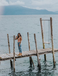 High angle view of woman standing on pier over sea