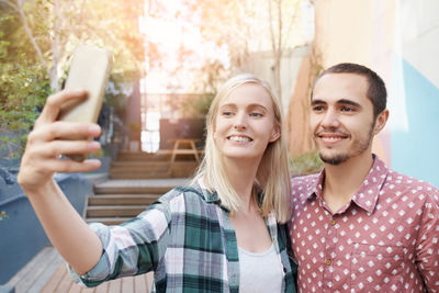 Smiling friends using mobile phone