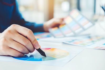 Midsection of woman holding color swatch at creative office