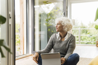 Mature woman using digital tablet while sitting at home