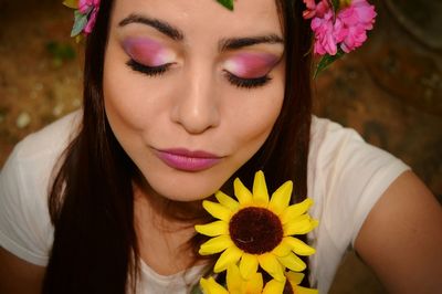 Close-up high angle view of young woman with eye make-up wearing flowers
