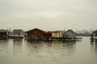 Houses by lake and buildings against sky