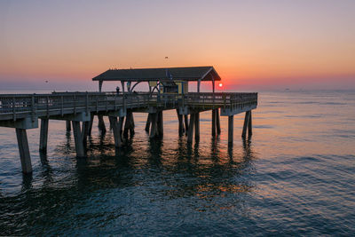 Pier over sea against sky during sunset