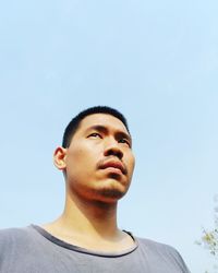 Portrait of young man looking away against sky