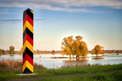 Information sign by lake against sky during sunset