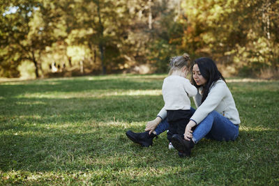 Mother and daughter sitting with daughter in autumn park