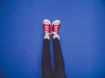 Low section of woman standing against blue background