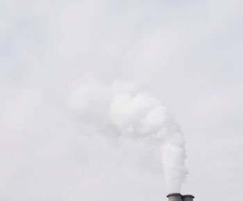 Low angle view of smoke emitting from chimney against sky