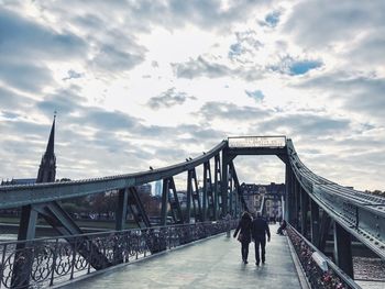 Low angle view of footbridge against cloudy sky