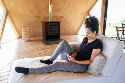 Woman using e reader while relaxing in a wooden dome tent.