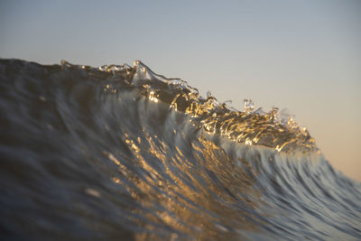 Close-up of water splashing against sky at sunset