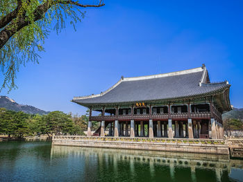 Built structure by lake against blue sky